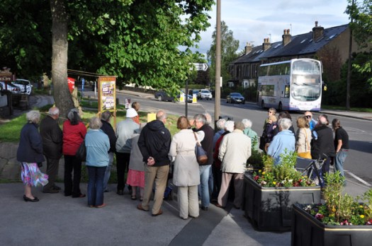 Residents watch a 51 bus pass the bus-themed well dressing outside Crosspool Tavern